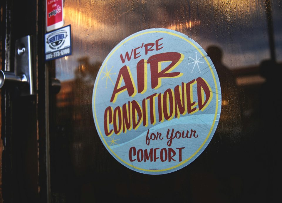 Air conditioned sign on a door emphasizing comfort, relevant to HVAC business services and selling air conditioning businesses.