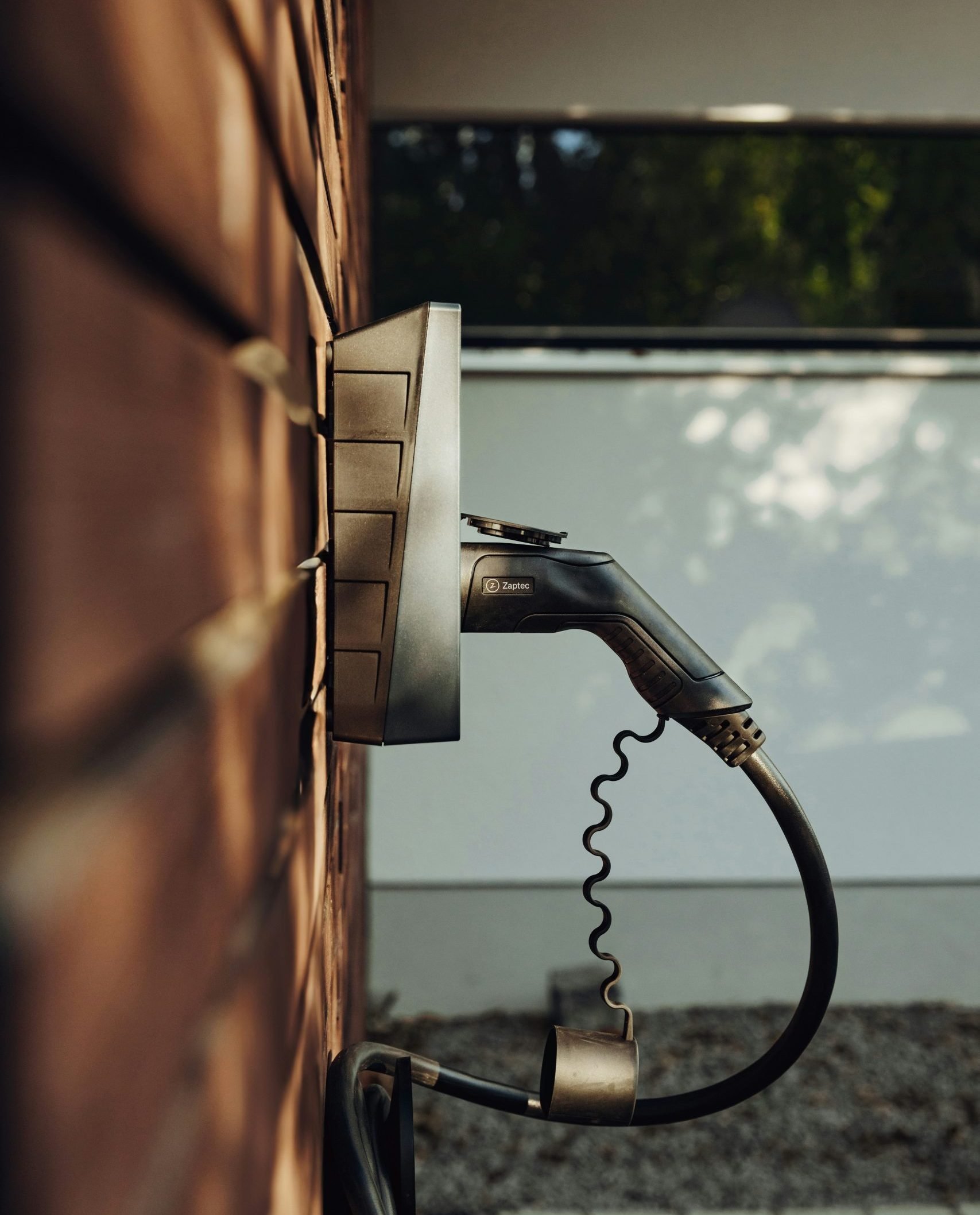 Electric vehicle charging station mounted on a brick wall, showcasing Zaptec branding, emphasizing modern electrical solutions for residential and commercial needs.