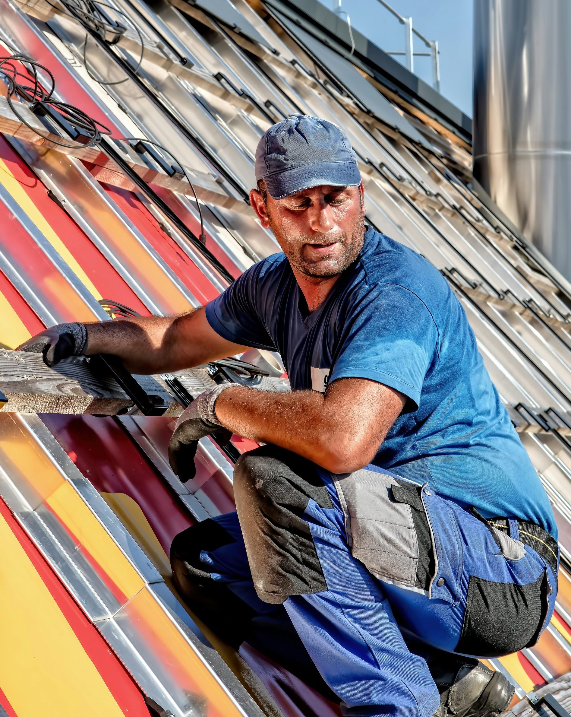 Worker installing solar panels on a colorful roof, emphasizing energy solutions and renewable energy initiatives.