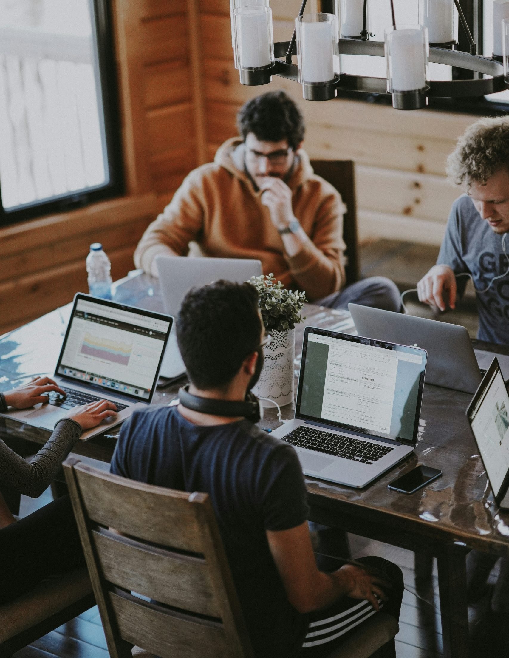 Group of people collaborating at a table with laptops, analyzing software business metrics and strategies, emphasizing teamwork in the tech industry.