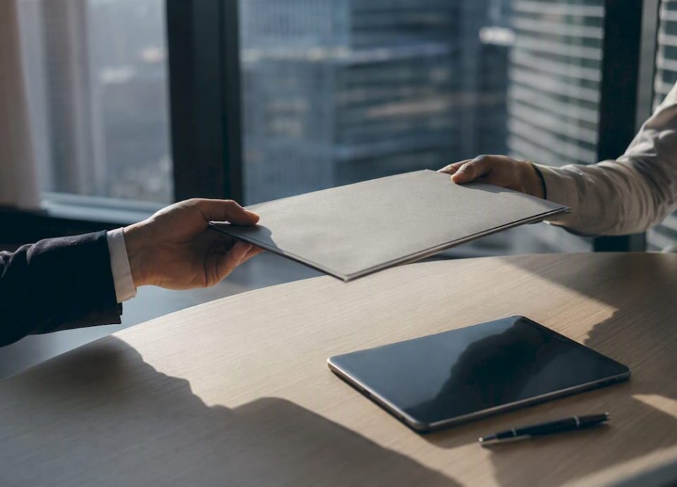 Hands exchanging business folder during negotiation