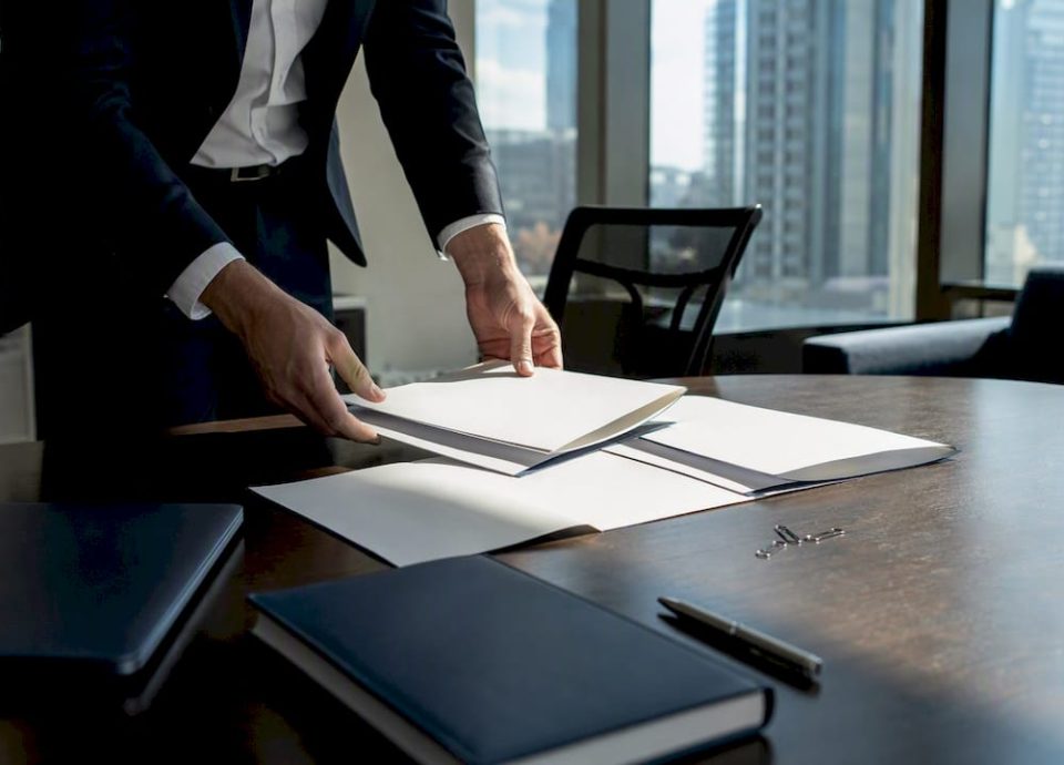Hands arranging folders for M&A agreement